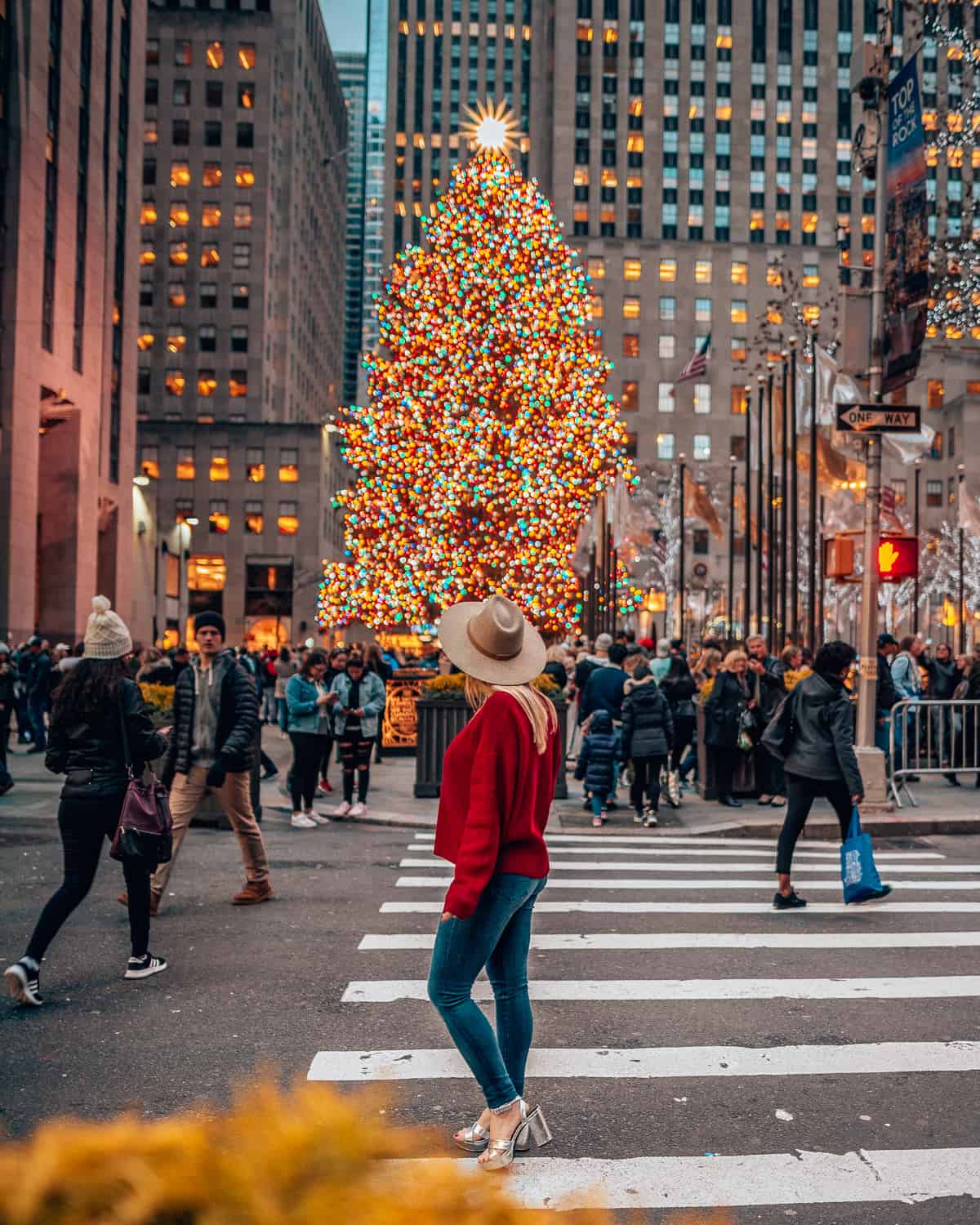 girl wearing red standing in front of a Christmas tree