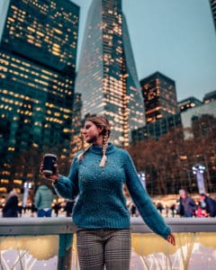 girl standing in front of a skating rink and sky scrapers