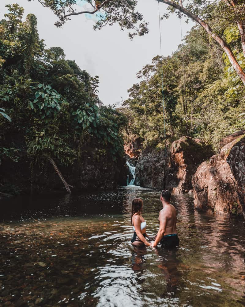couple standing in lagoon in rainforest