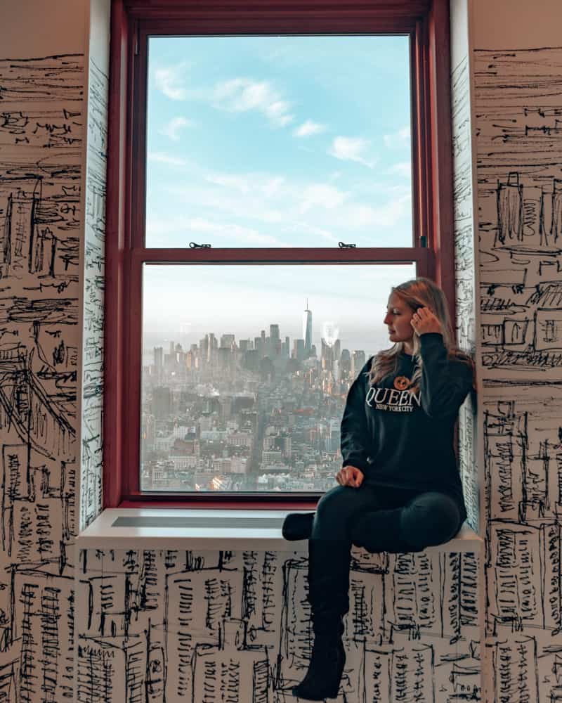 girl sitting in window with view of a city