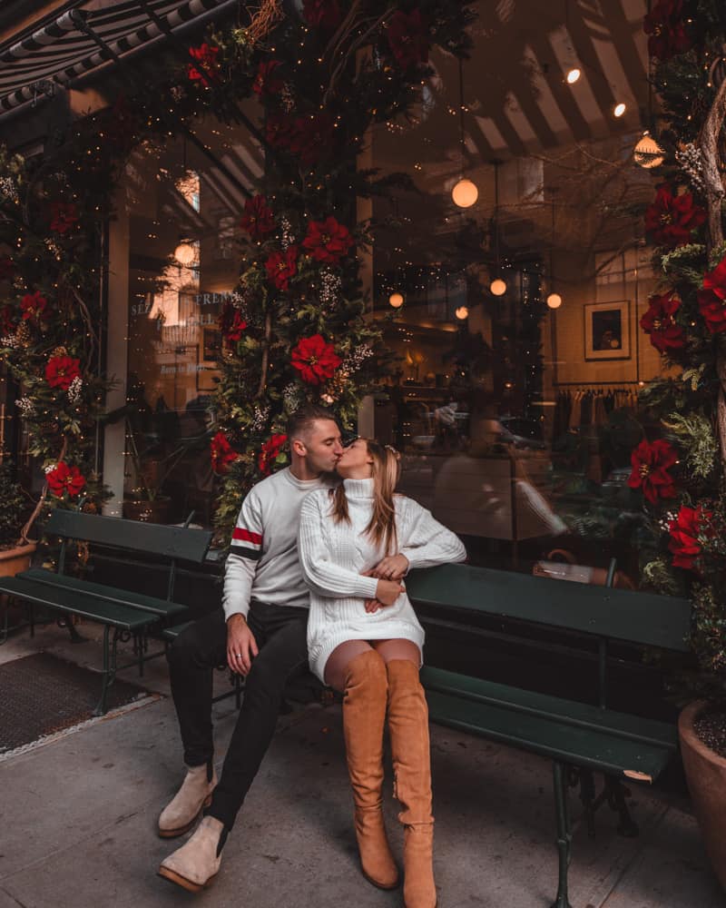 couple sitting in a bench in front of a boutique kissing