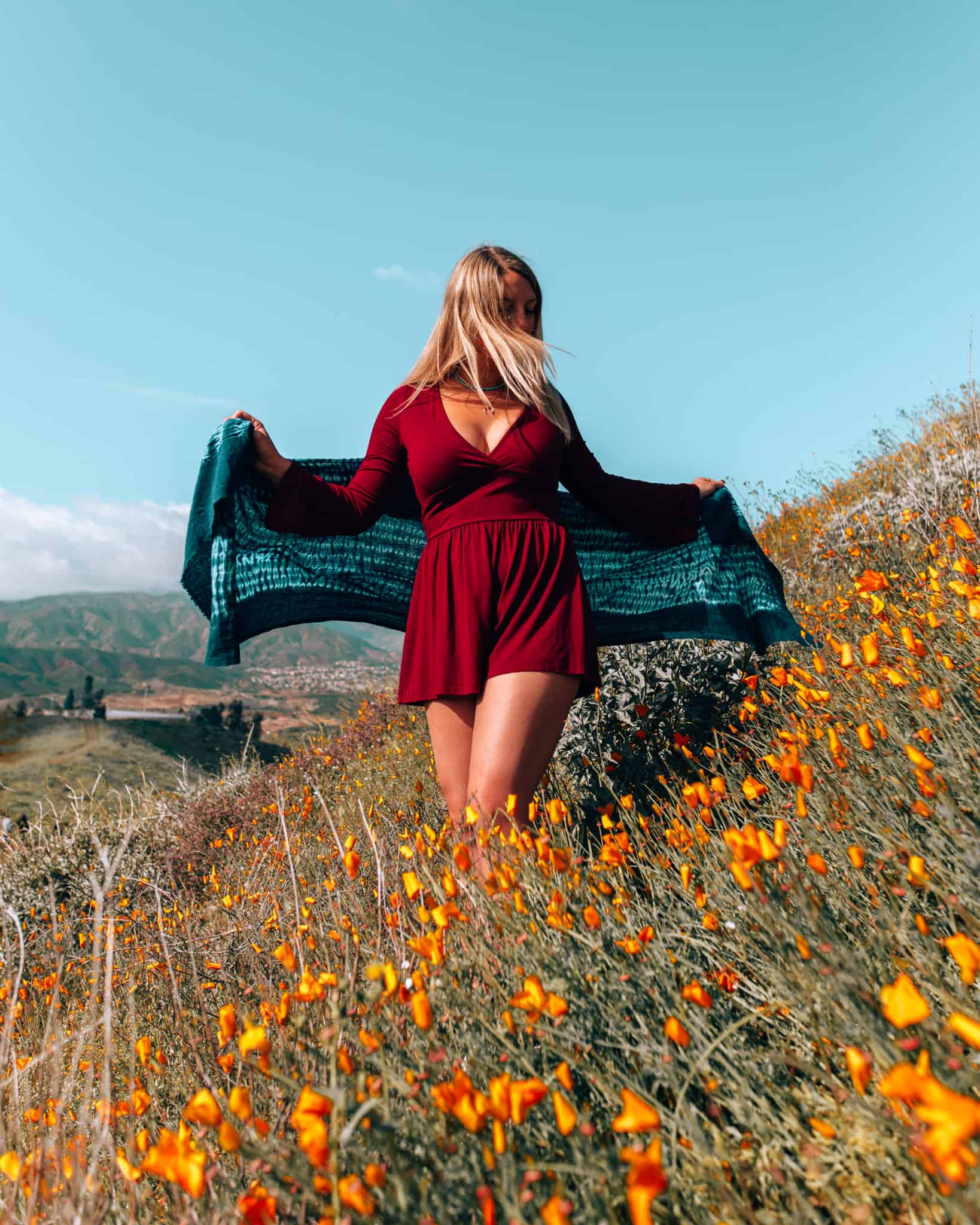 girl standing amongst poppies with a scarf